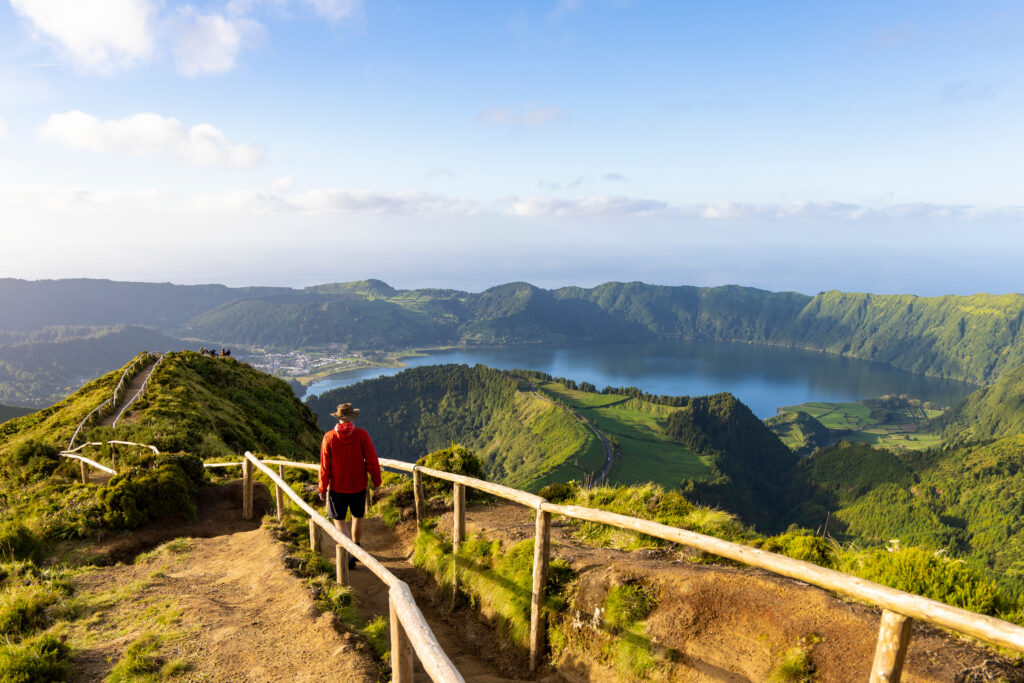 a man doing a hiking trail with a beautiful landscape of the green island of the Azores - São Miguel in Portugal