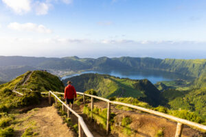 a man doing a hiking trail with a beautiful landscape of the green island of the Azores - São Miguel in Portugal